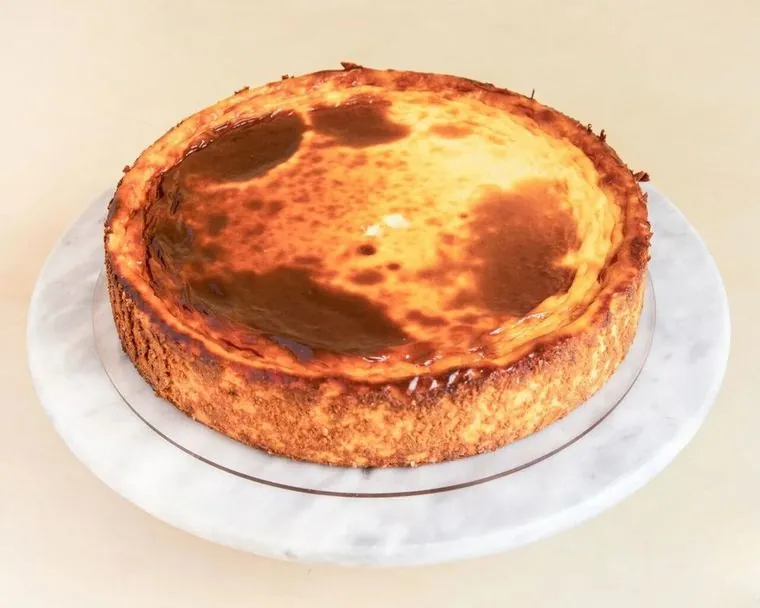 Cheesecake No tan clásica entera, con la superficie dorada y manchas de caramelo