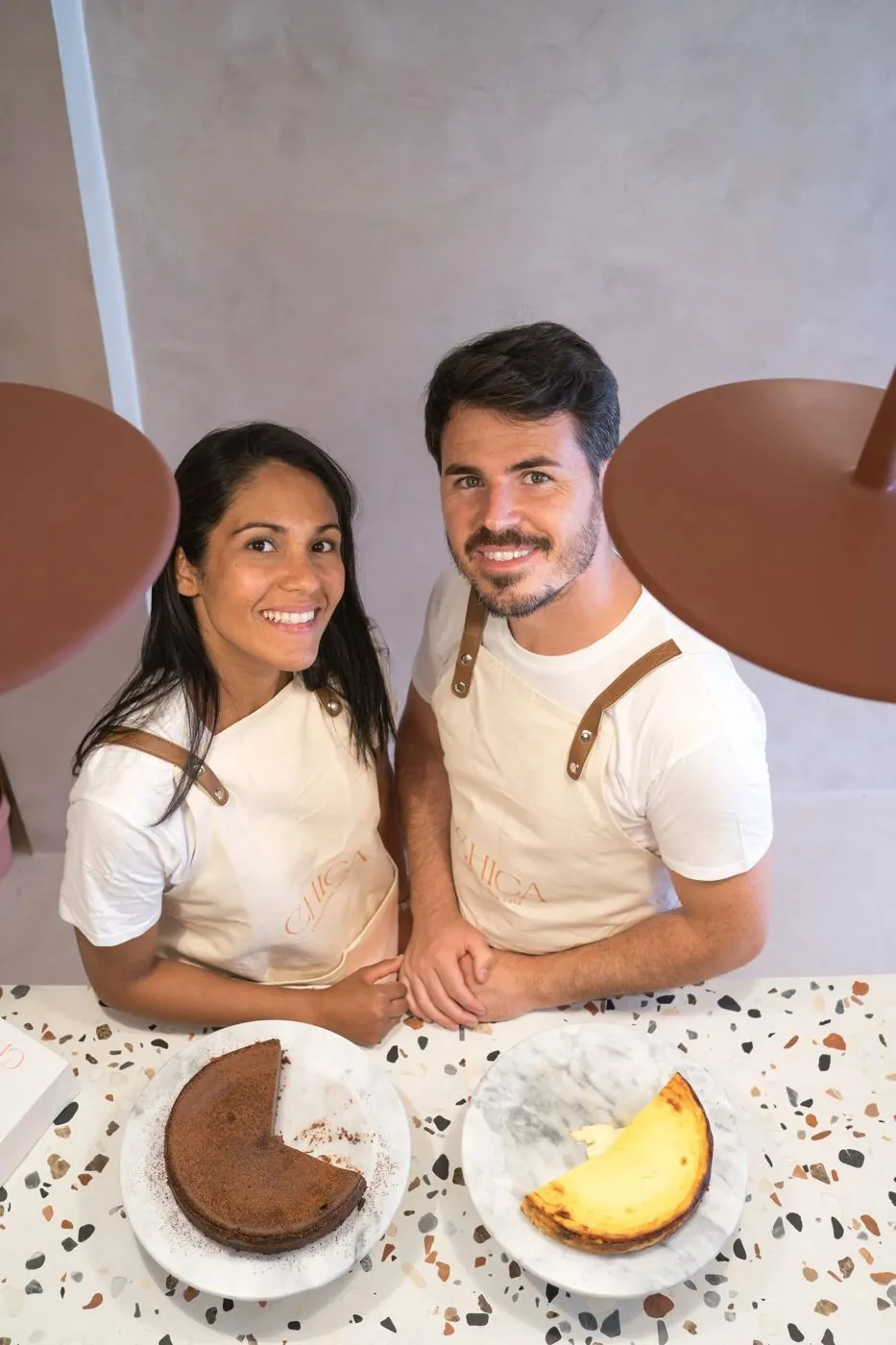 Las dos personas que llevan CHICA, con el delantal de la marca, en el mostrador de la tienda