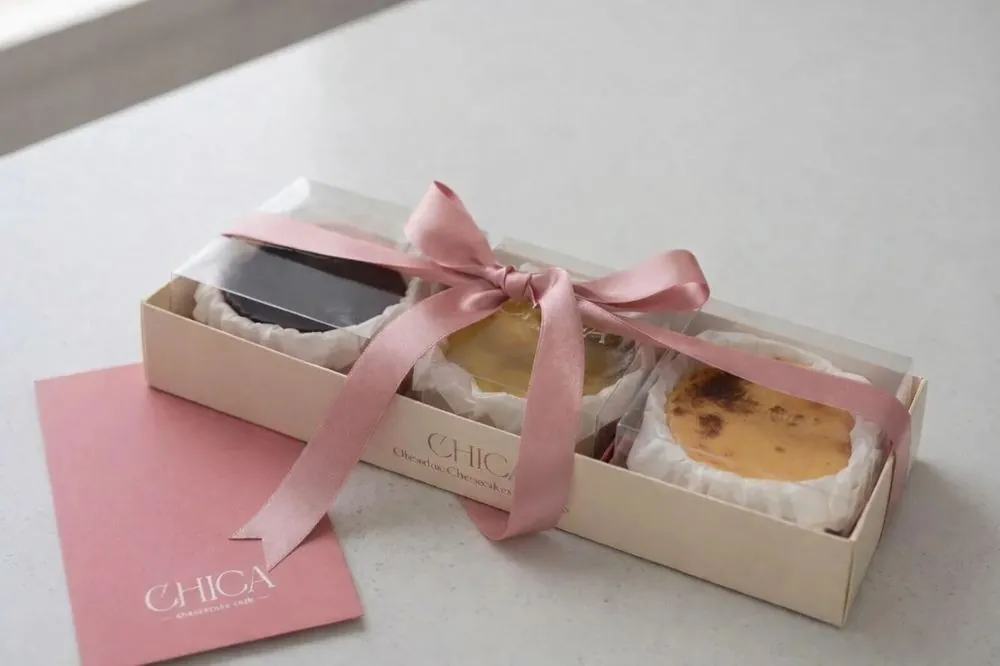 Caja con las tres cheesecakes pequeñas atada con un lazo rosa